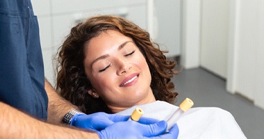 A dentist holding tubes of platelet-rich plasma and showing a female patient