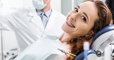 woman with braces smiling during dental checkup