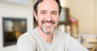 Man with brown hair smiling with grey shirt