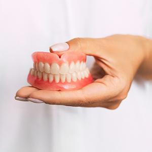 dentist holding dentures in hand  