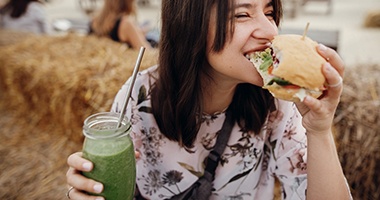 a person eating a sandwich and a smoothie