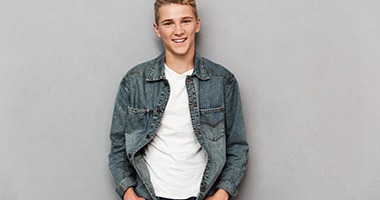 Smiling teenager in a denim jacket after completing Invisalign