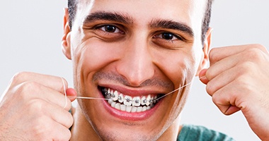Man flossing with braces in Medford 