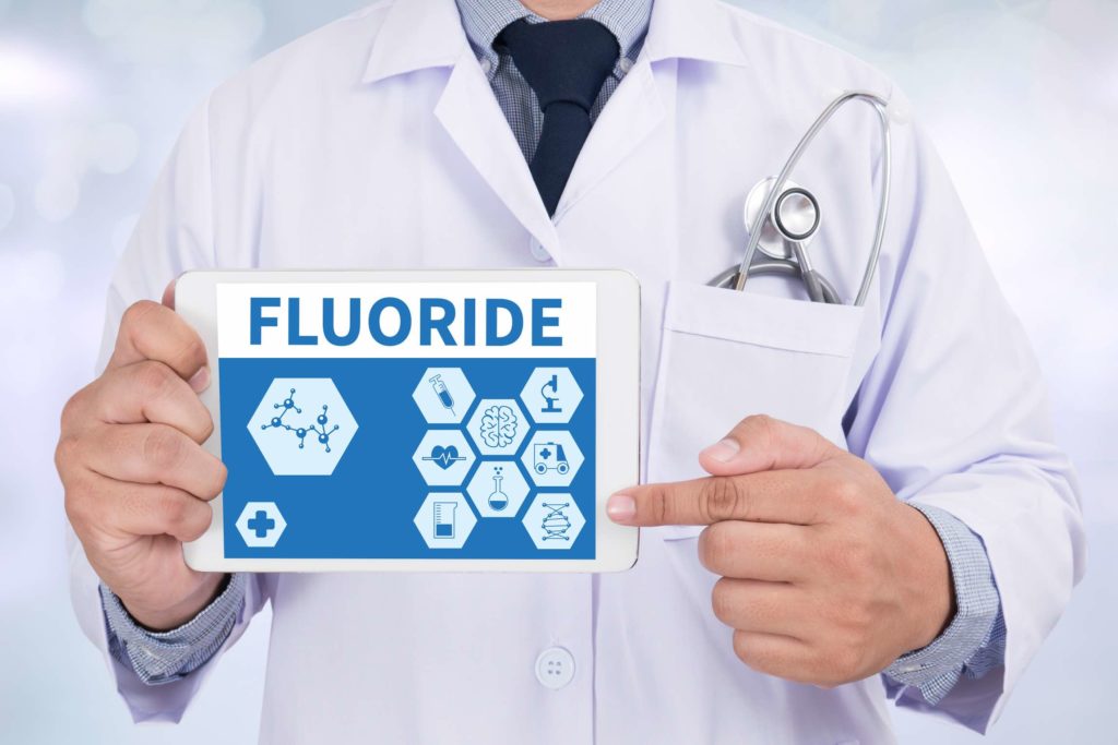 A dentist promoting cavity prevention holds a sign that reads, Fluoride