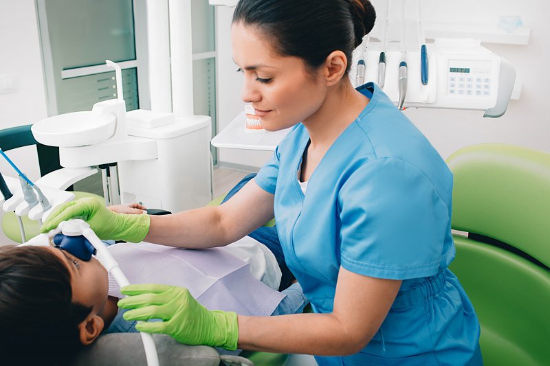 Dentist placing nitrous oxide mask on child patient