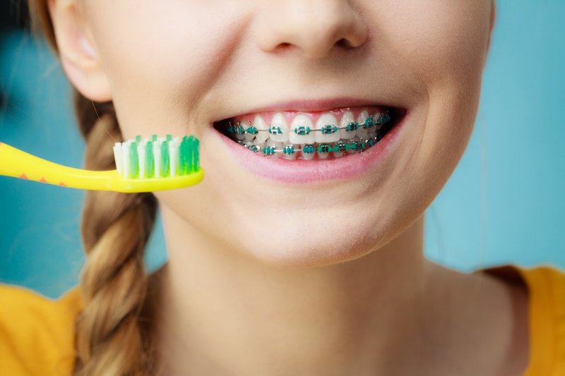 A patient brushing and flossing with braces